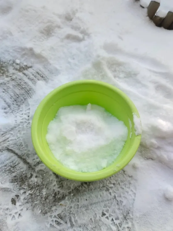 A green bowl filled with snow placed outdoors — showing how melted snow can be used as natural soft water for Calathea and other tropical houseplants.